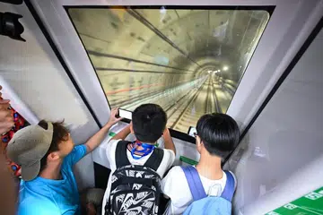 Leroy Lim (tengah), 10 tahun, bangun kira-kira jam 4.40 pagi untuk menaiki kereta api pertama yang tiba di stesen MRT Keppel.
