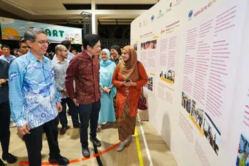 Perdana Menteri, Encik Lawrence Wong (depan, dua dari kiri); dan Pemangku Menteri Bertanggungjawab bagi Ehwal Masyarakat Islam merangkap Menteri Negara Kanan (Ehwal Dalam Negeri), Profesor Madya Dr Muhammad Faishal Ibrahim (depan, kiri) diberi taklimat oleh Naib Presiden II Persatuan Pemudi Islam Singapura (PPIS), Cik Nur Khairah Abdul Rahim (kanan), semasa sambutan ulang tahun ke-60 Singapura ‘SG60 Bersama: Satu Hati, Seribu Bakti’ di Wisma Geylang Serai pada 29 November.