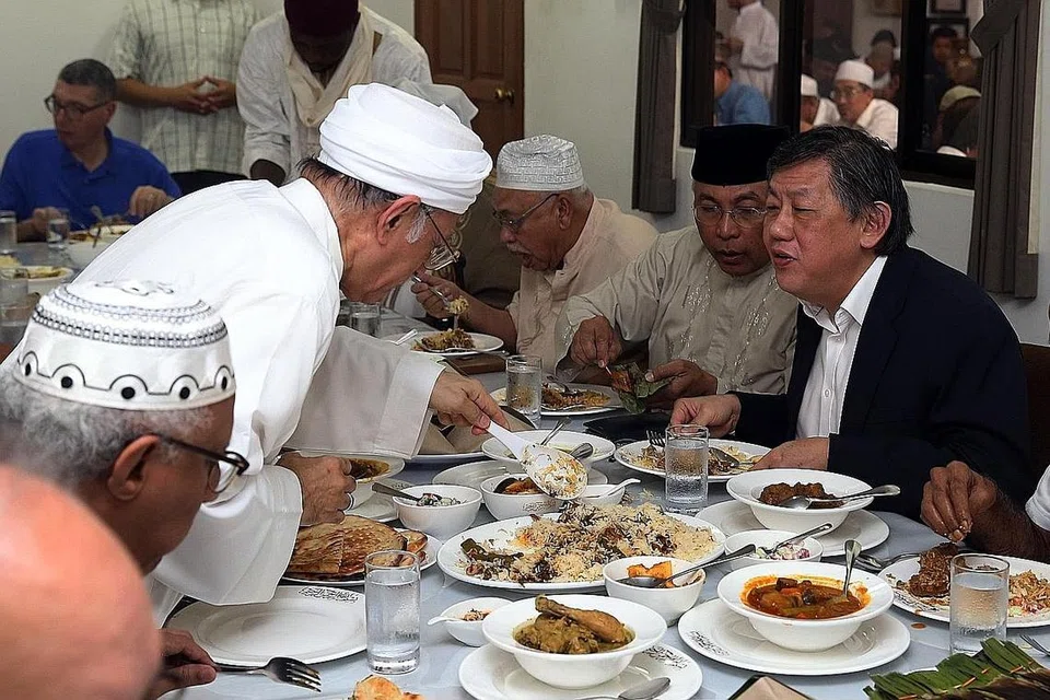 KUNJUNGAN TINGKATKAN PERSEFAHAMAN: Habib Hassan (dua dari kiri) mengambil lauk pauk dan membubuhnya di piring Paderi Yang (paling kanan) di majlis jamuan makan tengah hari yang diberikan sempena kunjungannya ke Masjid Ba'alwie selepas solat Jumaat semalam. - Foto BH oleh SEAH KWANG PENG