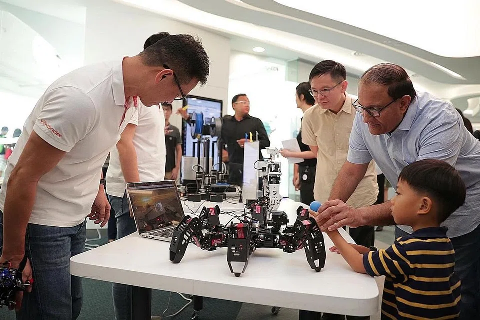 DEKATI MASYARAKAT: Encik Iswaran bermain permainan robotik bersama seorang pengunjung di libary@harbourfront sempena ulang tahun pertama perpustakaan itu semalam. Bersama mereka (tengah) ialah Ketua Pegawai Eksekutif (CEO) NLB, Encik Ng Cher Pong. - Foto BH oleh GIN TAY