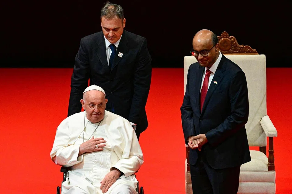 Paus (Pope) Francis (kiri, duduk) meninggalkan pentas di Pusat Budaya Universiti, Universiti Nasional Singapura, selepas menyampaikan ucapan pada 12 September. Beliau ditemani Presiden Tharman Shanmugaratnam (kanan).