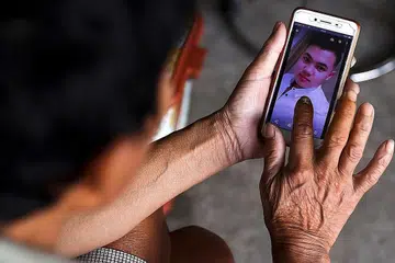 TINGGAL KENANGAN: Encik Hoang Van Lanh, bapa Hoang Van Tiep, salah seorang yang disyaki antara 39 mangsa pemerdagangan manusia dari Vietnam yang ditemui mati dalam trak sejuk beku di Essex, England, menunjukkan foto anaknya itu di telefon bimbit beliau di rumahnya di daerah Dien Chau, wilayah Nghe An, Vietnam, baru-baru ini. - Foto REUTERS