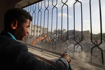 Penduduk Palestin di tengah-tengah serpihan bangunan melihat pekerja mengalihkan runtuhan bangunan akibat pengeboman Israel di Rafah, di selatan Jaluran Gaza, pada 21 April. 