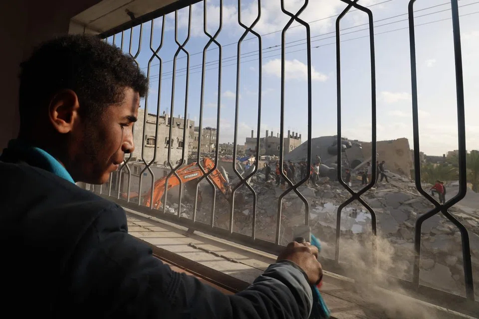Penduduk Palestin di tengah-tengah serpihan bangunan melihat pekerja mengalihkan runtuhan bangunan akibat pengeboman Israel di Rafah, di selatan Jaluran Gaza, pada 21 April. 