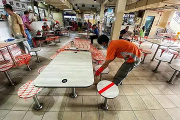 TIDAK BOLEH DUDUK UNTUK MAKAN: Seorang pekerja di Pusat Makanan Berseh di Jalan Besar meletakkan pelekat di kerusi sebagai menandakan pelanggan tidak boleh duduk di situ. - Foto BH oleh DESMOND WEE