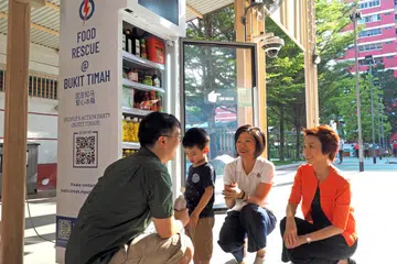 PETI SEJUK PINTAR: Pengerusi Sayap Wanita PAP, Cik Sim Ann (dua dari kanan), dan Naib Pengerusi Sayap Wanita PAP dan Cik Low Yen Ling (kanan), beramah dengan penduduk di depan peti sejuk pintar yang terletak di estet Toh Yi Drive.