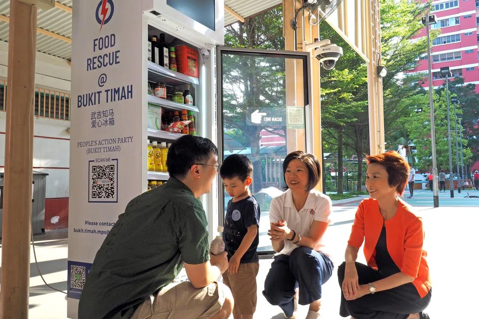 PETI SEJUK PINTAR: Pengerusi Sayap Wanita PAP, Cik Sim Ann (dua dari kanan), dan Naib Pengerusi Sayap Wanita PAP dan Cik Low Yen Ling (kanan), beramah dengan penduduk di depan peti sejuk pintar yang terletak di estet Toh Yi Drive.