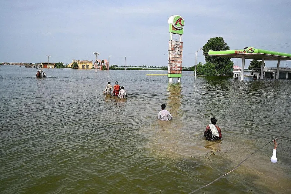 HARUNGI BANJIR: Penduduk yang dipindahkan mengharungi banjir untuk pulang ke rumah selepas hujan monsun lebat di daerah Dadu, wilayah Sindh di Pakistan semalam. - Foto AFP
