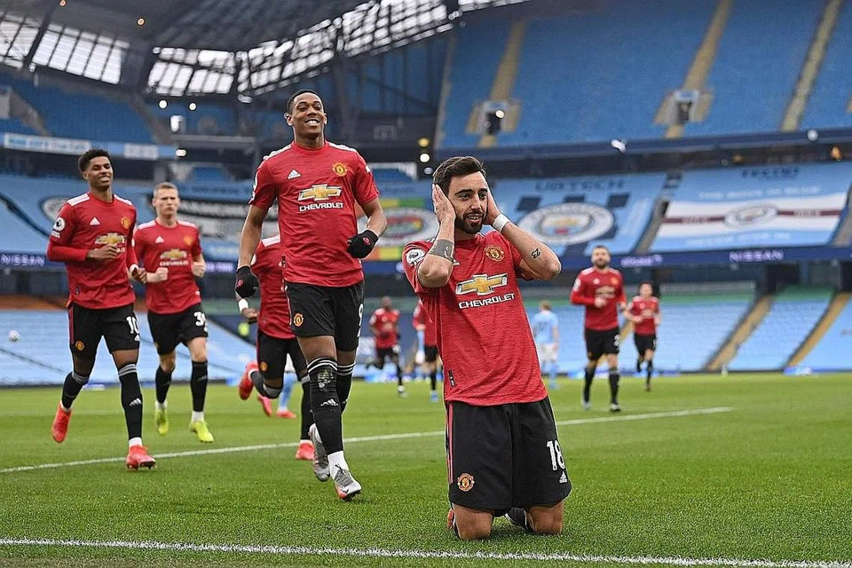 RAI KEJAYAAN: Pemain tengah Manchester United, Bruno Fernandes (melutut), merai bersama rakan sepasukannya kejayaan beliau menjaringkan gol pembukaan daripada tendangan penalti semasa menentang Manchester City di Stadium Etihad kelmarin. - Foto AFP 