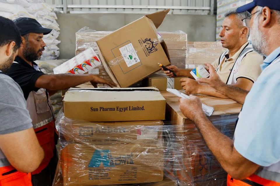 GOTONG-ROYONG: Pekerja Bulan Sabit Merah kelihatan mengaturkan bekalan bahan bantuan sebelum diagihkan kepada penduduk Palestin di Khan Younis, selatan Gaza.