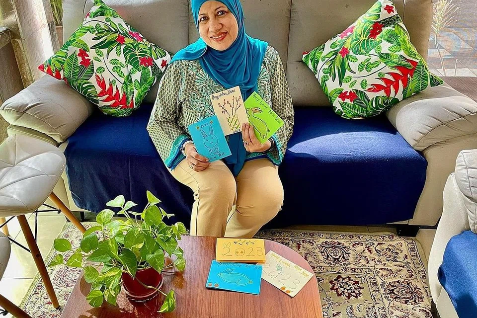 AGIH HABUAN: Cik Emily Yap bersama Encik Mikail Firas Abdul Jabbar mengagih habuan Tahun Baru Cina kepada 50 penerima di Clementi Meadows semalam, sementara Cik Nafisa Kapadia (atas) menyumbang dengan melukis kad Tahun Baru Cina untuk diberi kepada penerima habuan. - Foto-foto RANGKAIAN BELIA BUKIT TIMAH