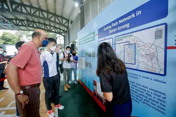 LALUAN BARU: Encik Tharman (kiri) dan Setiausaha Parlimen Kanan (Pengangkutan), Encik Baey Yam Keng (dua dari kiri), diberi taklimat di Taman Jurong Park semalam tentang laluan berbasikal baru di kawasan Taman Jurong. - Foto FACEBOOK LTA