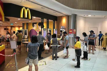 BERUSAHA CEGAH JANGKITAN: Pelanggan beratur untuk mendaftar masuk melalui kod QR dan suhu badan mereka diperiksa sebelum mereka dapat membuat pesanan untuk dibawa pulang di sebuah restoran McDonald's Isnin lalu. - Foto BH oleh KEVIN LIM
