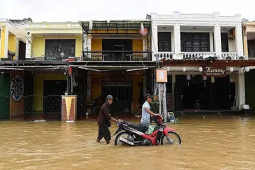 BANJIR SELEPAS TAUFAN: Dua pemuda dilihat menyorong motosikal setelah banjir berlaku akibat Taufan Noru di kota Hoi An, wilayah Quang Nam, Vietnam. - Foto-Foto AFP