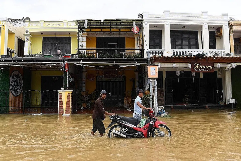 BANJIR SELEPAS TAUFAN: Dua pemuda dilihat menyorong motosikal setelah banjir berlaku akibat Taufan Noru di kota Hoi An, wilayah Quang Nam, Vietnam. - Foto-Foto AFP