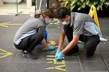 LANGKAH DILONGGAR: Pekerja membuka pelekat yang ditampal sebagai sebahagian daripada langkah pengurusan selamat di pintu masuk sebuah bangunan. - Foto BH oleh LIM YAOHUI