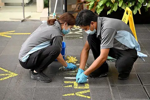 LANGKAH DILONGGAR: Pekerja membuka pelekat yang ditampal sebagai sebahagian daripada langkah pengurusan selamat di pintu masuk sebuah bangunan. - Foto BH oleh LIM YAOHUI