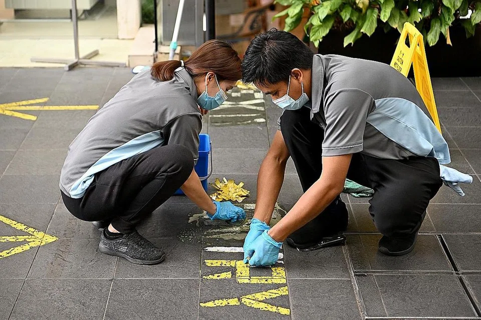 LANGKAH DILONGGAR: Pekerja membuka pelekat yang ditampal sebagai sebahagian daripada langkah pengurusan selamat di pintu masuk sebuah bangunan. - Foto BH oleh LIM YAOHUI