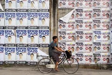 Seorang lelaki berbasikal melewati dinding penuh poster kempen calon senator Erwin Tulfo pada hari pertama tempoh kempen untuk pilihan raya pertengahan tempoh 12 Mei, di Manila, Filipina, 11 Februari