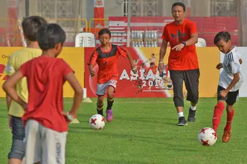 ASAH BAKAT: Fandi memberi bimbingan bola sepak kepada 20 kanak-kanak dari Pusat Khidmat Keluarga Ang Mo Kio dalam satu sesi klinik khas di Padang semalam. - Foto BH oleh DIOS VINCOY JR