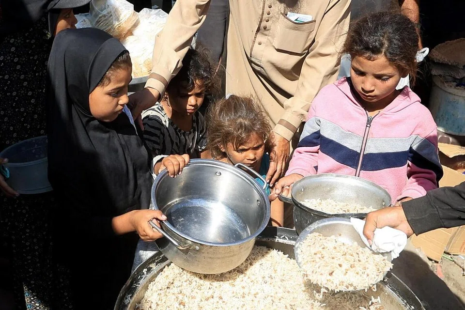 Kanak-kanak Palestin memegang periuk sambil berkumpul untuk menerima makanan daripada dapur amal di Deir Al-Balah, tengah Jaluran Gaza, 8 Oktober 2025.
