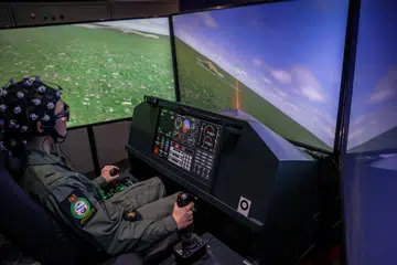 TEKNOLOGI SIMULASI: Seorang  juruterbang pelatih RSAF kelihatan sedang menyerang dan menembak kapal terbang musuh dalam skrin menerusi sistem simulasi Projek SOAR yang berbentuk persis kokpit jet pejuang.
