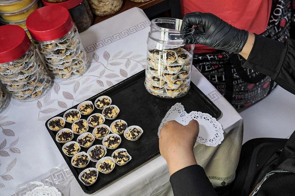 KUIH RAYA: Bekerja dari ruang tamu di rumah flatnya di Yishun, Cik Mardiana Hassan menyusun kuih Raya di dalam botol sebelum ia dijualkan kepada pelanggan dan kedai di kawasan Yishun.