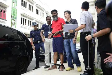 DIHUKUM GANTUNG: Rasheed Muhammad (berbaju merah) diiringi pegawai polis di Rowell Road pada 19 Jun 2014. Rasheed dan Ramzan (tidak ada dalam gambar), kededuanya dari Pakistan, dijatuhi hukuman gantung sampai mati semalam setelah didapati bersalah membunuh Encik Muhammad Noor pada 11 Jun 2014. - Foto fail