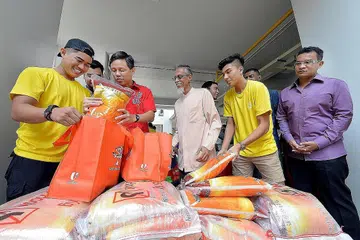 IHSAN RAMADAN: Encik Chan (berbaju merah) membantu membungkus habuan untuk diberi kepada penerima bantuan dengan relawan Encik Muhd Shazwan Nur Rhymie (kiri) dan Encik Danial Irfan Shah (dua dari kanan) dengan disaksikan (dari kanan) Timbalan Presiden 4PM, Encik Mohd Hairil Johari, dan presiden badan itu, Encik Izzuddin Taherally. - Foto M.O. SALLEH