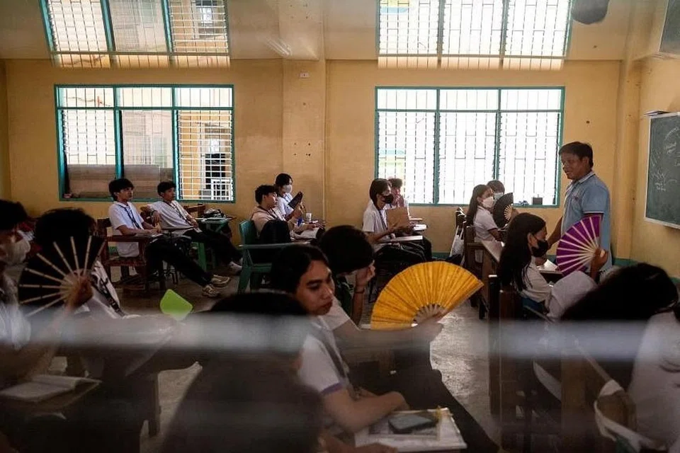 Pelajar menengah atas gunakan kipas tangan semasa mereka menghadiri kelas di Sekolah Tinggi Komanwel, di Quezon City, Metro Manila, pada 18 April gara-gara cuaca panas terik melanda Asia. 