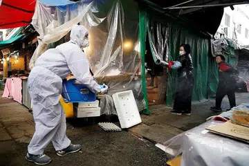 KEKANG PENULARAN VIRUS: Seorang kakitangan dari syarikat penyahkuman melakukan kerja-kerja pengekangan penularan kuman dan virus di pasar tradisional di Seoul, Korea Selatan, semalam. - Foto REUTERS