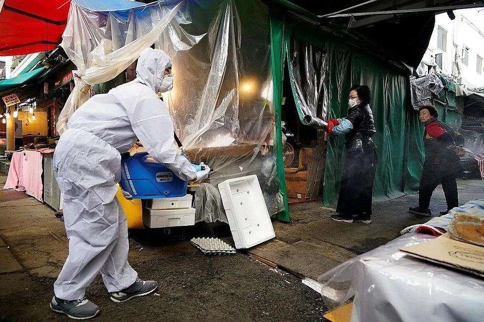 KEKANG PENULARAN VIRUS: Seorang kakitangan dari syarikat penyahkuman melakukan kerja-kerja pengekangan penularan kuman dan virus di pasar tradisional di Seoul, Korea Selatan, semalam. - Foto REUTERS
