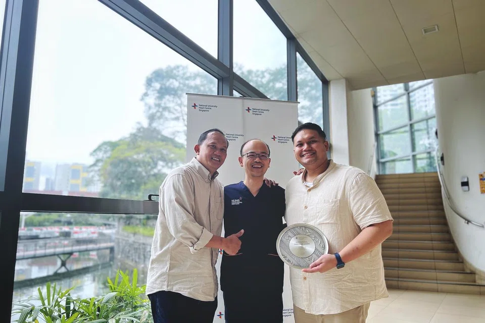 Encik Azmi, yang memegang plak Anugerah Penjaga Berinspirasi, bersama Dr Yeo Wee Tiong, Pakar Runding Kanan, Jabatan Kardiologi, NUHCS, dan ayahnya Encik Azmi Said.