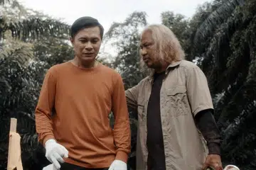 UBAH PENAMPILAN: Rafaat Hamzah (kanan) memutihkan rambut, menyimpan misai, mengubah suara dan cara berbual untuk bawakan watak penggali kubur berusia yang bijaksana, Abang Li. Bersamanya, Suzairhe Sumari, selaku jurubina Shaari yang juga penggali kubur sambilan.
