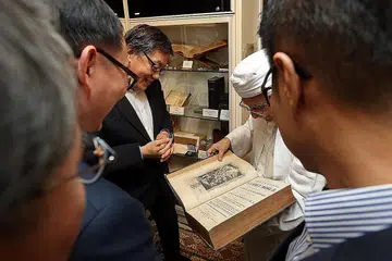 TAK KENAL MAKA TAK CINTA: Habib Hassan (berserban) menunjukkan sebuah kitab lama yang dijadikan bahan koleksi bersejarah di Masjid Ba'alwie kepada Paderi Yang (Tengah). - Foto BH oleh SEAH KWANG PENG