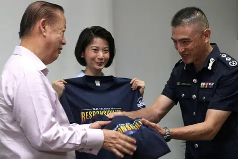 TANGGUNGJAWAB SEMUA: Cik Sun (tengah) dipersembahkan kemeja-T yang dicetak Take Road to Responsibility, tema edisi kedua inisiatif, Use Your RoadSense, oleh SAC Lim (kanan) dan Pengerusi Majlis Keselamatan Jalan Raya Singapura Encik Bernard Tay. - Foto BH oleh ZAIHAN YUSOF