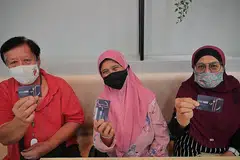 GEMBIRA DENGAN KAD BARU: (Dari kiri) Encik Othman Mustari, 70 tahun, Cik Norlini Mansor, 70 tahun dan Cik Mona Samin, 68 tahun, melahirkan perasaan gembira menerima kad bank FBSG yang diagihkan untuk inisiatif baru Tap-A-Meal. - Foto BH oleh JASON QUAH