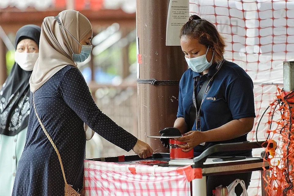 LANGKAH SELAMAT: Kad pengenalan pengunjung di Pasar Geylang Serai (atas) perlu diimbas sebagai sebahagian langkah 'SafeEntry' bagi tujuan menjejak kontak. - Foto BH oleh JOEL CHAN