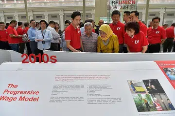 PENGAJARAN SEJARAH: Puan Halimah (berbaju kuning) meneliti Pameran 'ReUnion' oleh NTUC yang meraikan ulang tahun ke-50 Seminar Kesatuan Perdagangan mengenai Pemodenan Gerakan Buruh. Turut menemaninya ialah Presiden NTUC, Cik Mary Liew (kanan); Setiausaha Agung NTUC, Encik Ng Chee Meng (belakang Puan Halimah) dan para pemimpin gerakan buruh yang lain. - Foto BH oleh NG SOR LUAN