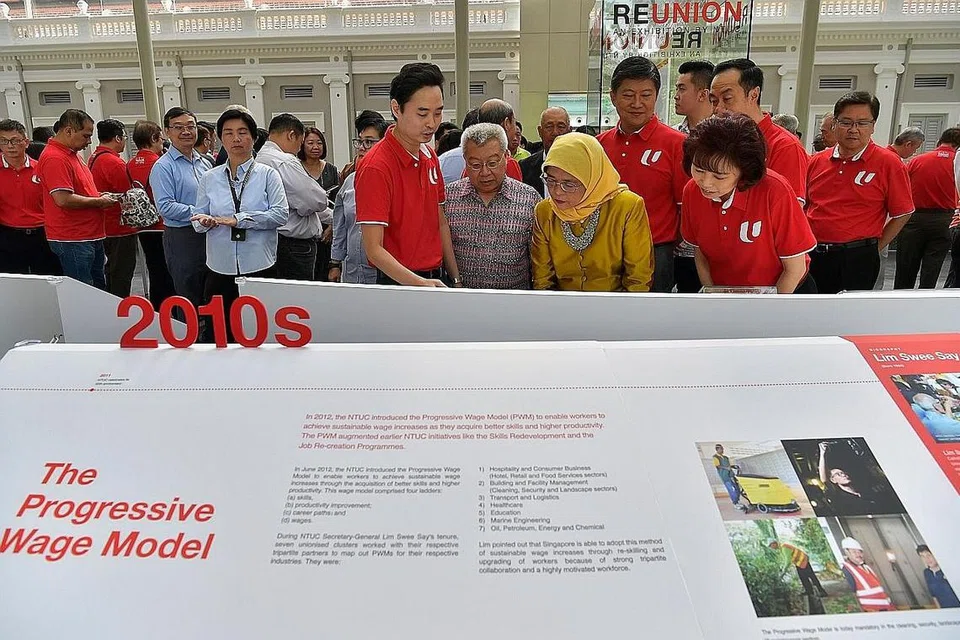 PENGAJARAN SEJARAH: Puan Halimah (berbaju kuning) meneliti Pameran 'ReUnion' oleh NTUC yang meraikan ulang tahun ke-50 Seminar Kesatuan Perdagangan mengenai Pemodenan Gerakan Buruh. Turut menemaninya ialah Presiden NTUC, Cik Mary Liew (kanan); Setiausaha Agung NTUC, Encik Ng Chee Meng (belakang Puan Halimah) dan para pemimpin gerakan buruh yang lain. - Foto BH oleh NG SOR LUAN