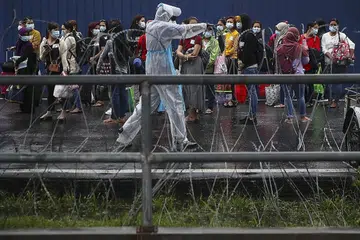JALANI RAWATAN: Kakitangan Top Glove menunggu di luar kilang untuk dipindahkan ke hospital berdekatan asrama mereka di Setia Alam, di luar Kuala Lumpur, kelmarin. - Foto EPA-EFE