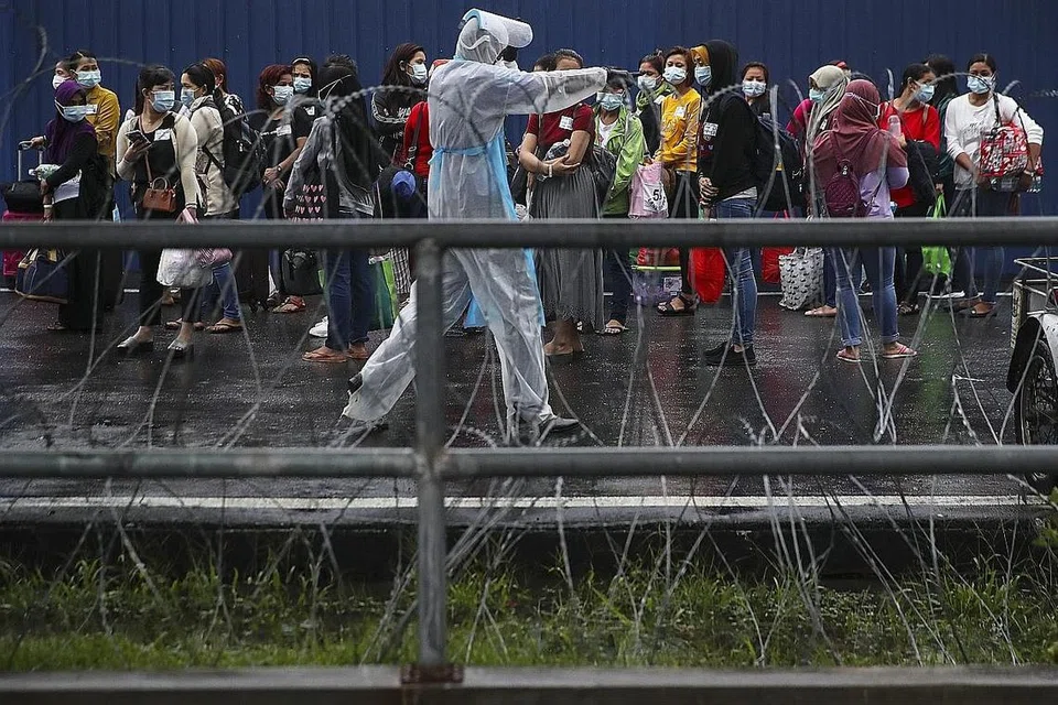 JALANI RAWATAN: Kakitangan Top Glove menunggu di luar kilang untuk dipindahkan ke hospital berdekatan asrama mereka di Setia Alam, di luar Kuala Lumpur, kelmarin. - Foto EPA-EFE