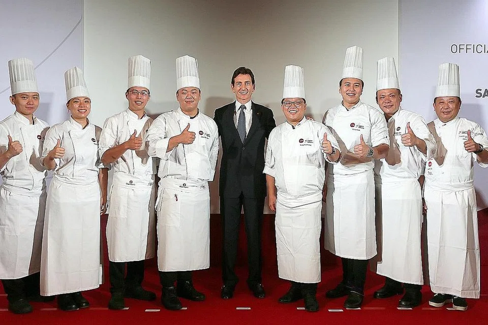 MENU BARU: (tengah) Encik Alex Hungate, CEO Sats Ltd, bersama pasukan cef yang bertungkus lumus mengusahakan serta mencari inspirasi sejak Februari lalu, untuk menghasilkan menu baru yang dijangka menawarkan pengalaman menjamu selera lebih menarik dalam penerbangan. - Foto BH oleh JONATHAN CHOO