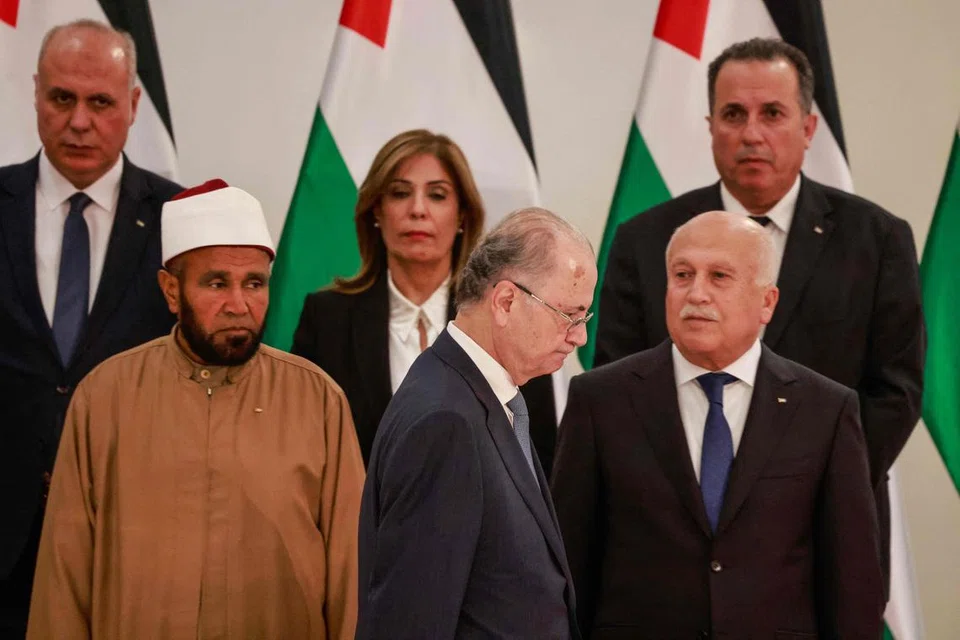 Perdana Menteri Palestin yang baru dilantik, Encik Mohammed Mustafa (tengah), berjalan melintasi menteri lain, semasa majlis angkat sumpah di Ramallah, Tebing Barat.