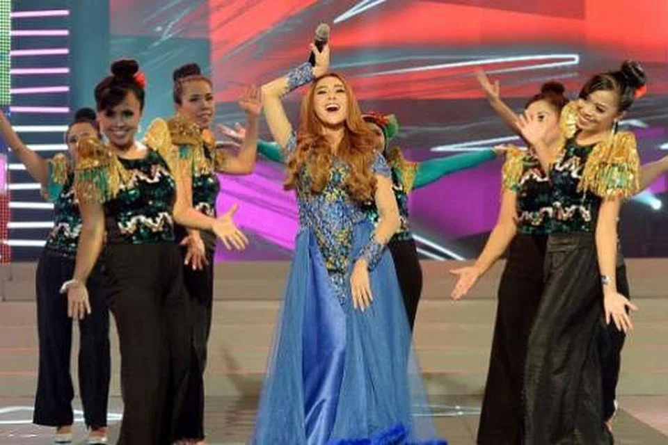 PERSEMBAHAN BERTENAGA: Penyanyi dangdut Indonesia, Cita Citata, menghiburkan peminat dalam Fiesta Pos T.K.I. kelmarin. Di kiri dan kanannya ialah penari terdiri daripada pembantu rumah dari Indonesia. - Foto TAUFIK A. KADER