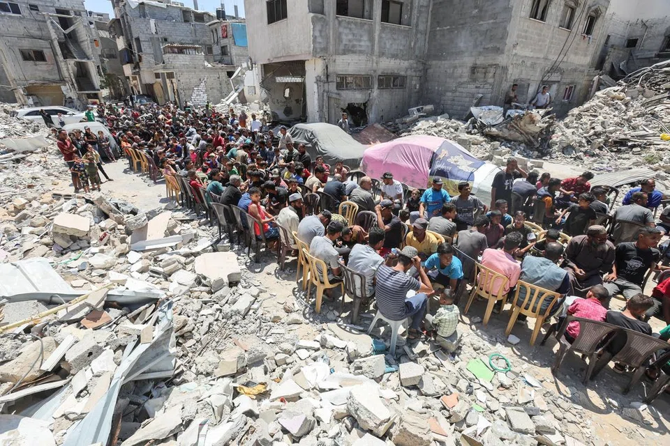 Penduduk Palestin makan bersama juadah yang dimasak oleh sebuah badan amal di tapak bangunan yang musnah akibat serangan Israel di Khan Younis, Gaza, pada 30 Mei. Serangan Israel ke atas Rafah menghentikan aliran bantuan Pertubuhan Bangsa-Bangsa Bersatu (PBB) ke wilayah Palestin itu.