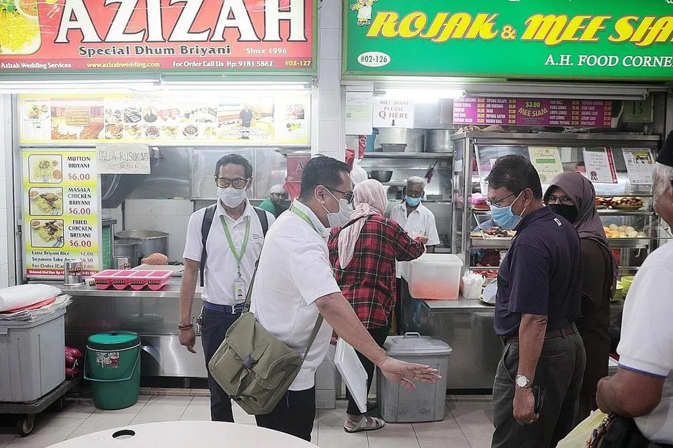 ALAH BISA TEGAL BIASA: Pegawai penguat kuasa Agensi Sekitaran Kebangsaan(NEA) membantu pelanggan di pusat makanan untuk memastikan mereka menjaga jarak demi kepentingan bersama. - Foto BH oleh JASON QUAH 