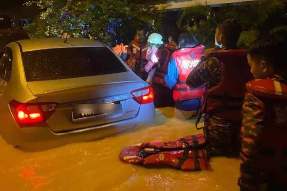 Anggota Bomba membantu menyelamatkan penduduk kampung di Sepang, Selangor, yang terperangkap dalam banjir.