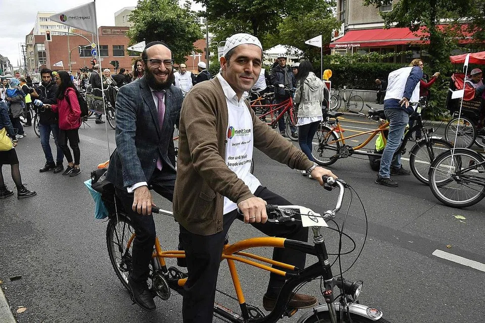 PUPUK KEHARMONIAN: Imam Osman Oers (depan) dan Rabai Akiva Weingarten (belakang) mengambil bahagian dalam acara berbasikal bersama dalam usaha mempromosi semangat saling menghormati antara agama dan menentang perkauman serta anti-Semitisme. - Foto AFP