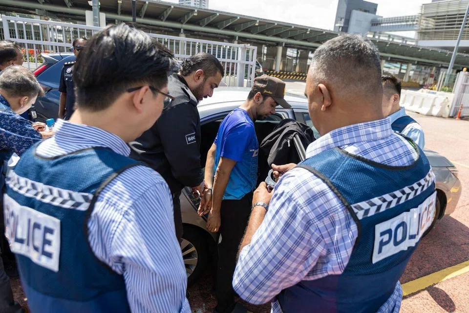 Mohd Mazuan Abdullah (digari di tengah), 39 tahun, seorang warga Malaysia, telah diserahkan kepada pihak Singapura pada 16 Mac. Dia kini berdepan tiga pertuduhan mencuri di mahkamah Singapura. 